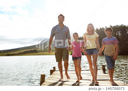 Family, children and pier by lake for holding hands in portrait, happy or vacation with love in summer sunshine. Mom, dad and kids with smile, care or bonding on walk by river for holiday in Colorado 140788071