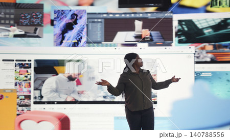 Woman views many online video streams across a large digital wall interface. 140788556