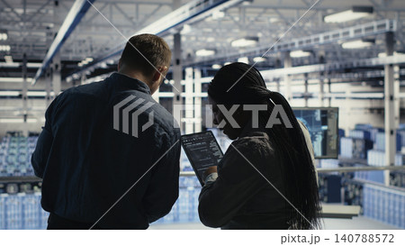 Data center colleagues respond to a warning alert on a laptop while troubleshooting server room systems. Data center colleagues respond to a warning alert on a laptop while troubleshooting server room systems. 140788572