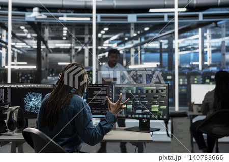 Data center worker monitors system performance and troubleshoots software issues affecting server operations. Data center worker monitors system performance and troubleshoots software issues affecting server operations. 140788666