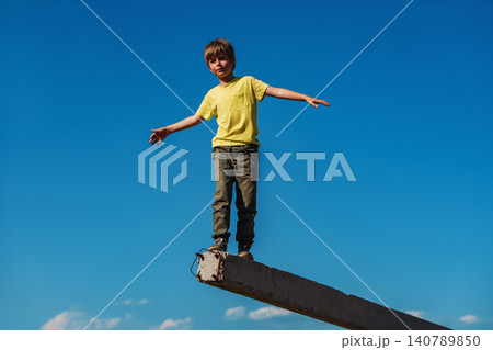 Boy walking and balancing on blue sky backgrounds Boy walking and balancing on blue sky backgrounds 140789850