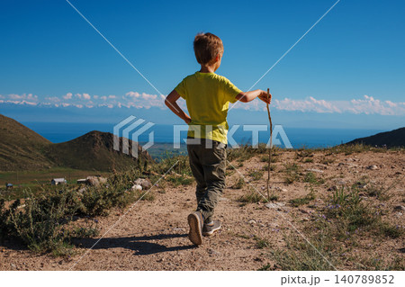 Boy hiker with stick walks on a mountain trail 140789852