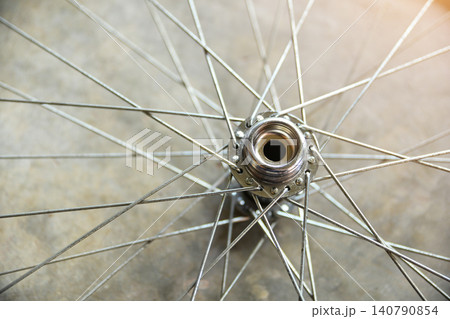 Close-up top view of a shiny metallic bicycle wheel hub with steel spokes radiating outwards, abstract mechanical and transportation concept. 140790854