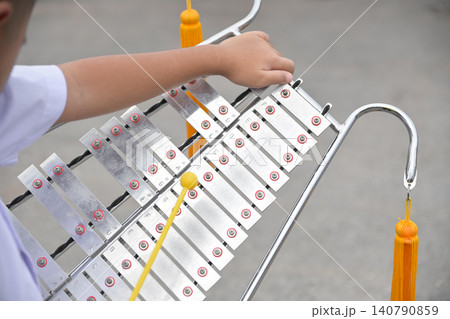 Child's hand holding and playing a portable metallic xylophone bell lyra. Musical education and youth marching band concept. Child's hand holding and playing a portable metallic xylophone bell lyra. Musical education and youth marching band concept. 140790859