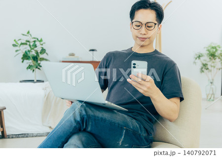ソファーに座ってスマホを使う男性 140792071