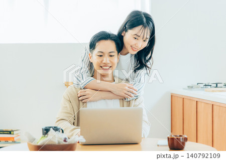 リビングでパソコンを見る若い夫婦 リビングでパソコンを見る若い夫婦 140792109