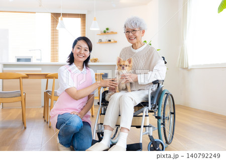 介護　犬を可愛がるシニア女性と介護士 140792249