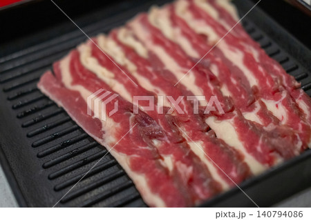 A close-up shot of sliced raw meat, arranged on a plate, ready to be cooked in a hot pot A close-up shot of sliced raw meat, arranged on a plate, ready to be cooked in a hot pot 140794086
