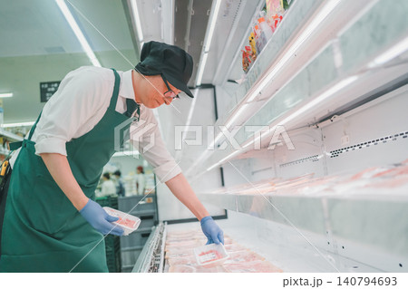 スーパーの精肉売り場で豚肉を整理する男性店員の上半身 スーパーの精肉売り場で豚肉を整理する男性店員の上半身 140794693