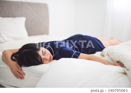 ベッドで横たわり休息する若い女性 ベッドで横たわり休息する若い女性 140795063