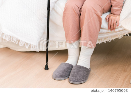 ベッドから起き上がる膝を痛がるパジャマ姿ののシニア女性（膝,膝痛） 140795098