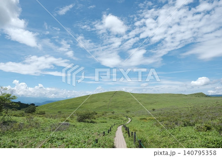 青空のもと新緑の丘へ続く木道、爽快な夏の高原ハイキング風景 青空のもと新緑の丘へ続く木道、爽快な夏の高原ハイキング風景 140795358