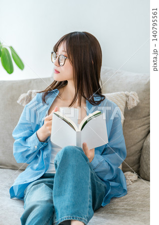 リビングのソファーに座り本,小説を読むオシャレなアジア人女性 140795561
