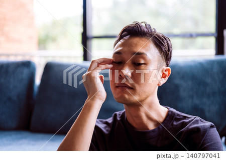 ソファで目を押さえる男性 140797041