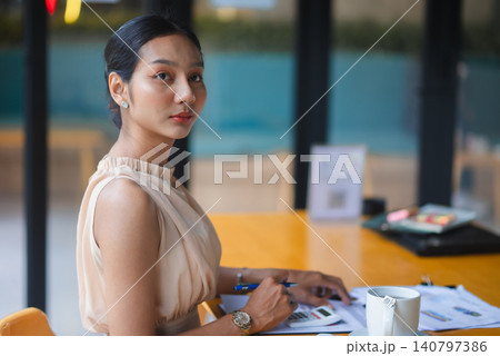 Confident businesswoman working with calculator and financial documents in modern office, looking at camera, ideal for accounting, consulting, planning, entrepreneurship, and productivity themes. Confident businesswoman working with calculator and financial documents in modern office, looking at camera, ideal for accounting, consulting, planning, entrepreneurship, and productivity themes. 140797386