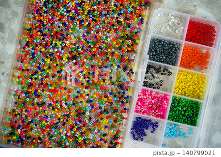 Close up of colorful seed beads in square sections pink shades, flat lay Close up of colorful seed beads in square sections pink shades, flat lay 140799021