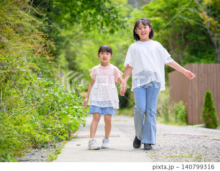 遊歩道を手をつないで歩く姉妹 遊歩道を手をつないで歩く姉妹 140799316