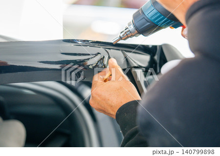 A car wrapping specialist applies a polyurethane film to the car. Detailer PPF 140799898