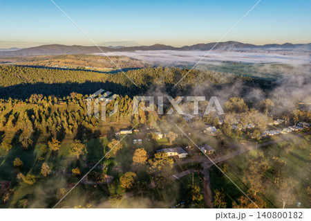 Aerial view over the Lake Keepit campgrounds as fog drifts across the surrounding rural landscape beneath soft sunrise light in NSW, Australia. 140800182