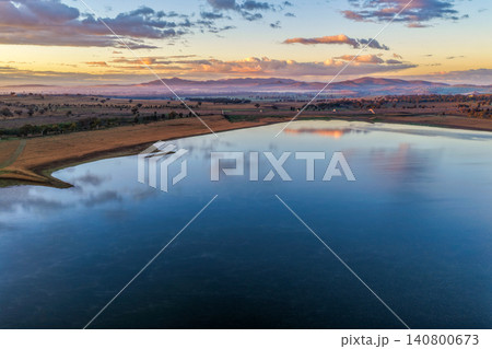Aerial view at dawn over Lake Keepit featuring the dam wall, expansive reservoir and a foggy rural landscape beneath soft golden morning light in NSW, Australia. Aerial view at dawn over Lake Keepit featuring the dam wall, expansive reservoir and a foggy rural landscape beneath soft golden morning light in NSW, Australia. 140800673