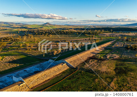 Aerial scene showcasing the Lake Keepit dam wall leading into the surrounding rural landscape, highlighting the expansive reservoir, engineering infrastructure and natural beauty of the region in NSW Aerial scene showcasing the Lake Keepit dam wall leading into the surrounding rural landscape, highlighting the expansive reservoir, engineering infrastructure and natural beauty of the region in NSW 140800761