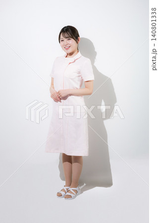 ピンクのナース服を着た笑顔で案内や歯科医院の受付のポーズをする美容系の看護師、歯科衛生士、歯科助手等 ピンクのナース服を着た笑顔で案内や歯科医院の受付のポーズをする美容系の看護師、歯科衛生士、歯科助手等 140801338