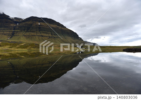 Mountain ridge perfectly reflected on a glassy lake surface, Iceland Mountain ridge perfectly reflected on a glassy lake surface, Iceland 140803036