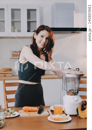 Woman preparing green smoothie in bright kitchen with fresh fruits and vegetables, healthy eating lifestyle moment in natural daylight Woman preparing green smoothie in bright kitchen with fresh fruits and vegetables, healthy eating lifestyle moment in natural daylight 140803661