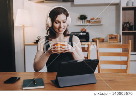 Woman preparing green smoothie in bright kitchen with fresh fruits and vegetables, healthy eating lifestyle moment in natural daylight 140803670