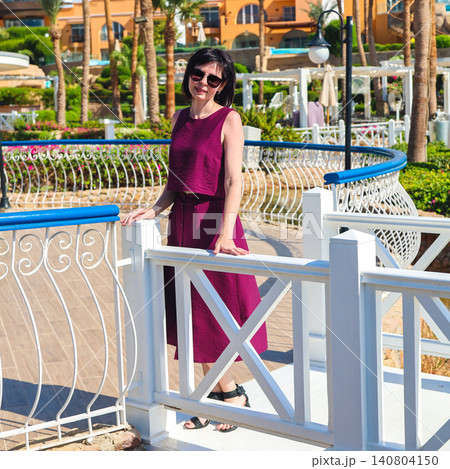 Portrait of a beautiful mature woman smiling on a sunny Egyptian resort with palm trees and blue sky Portrait of a beautiful mature woman smiling on a sunny Egyptian resort with palm trees and blue sky 140804150