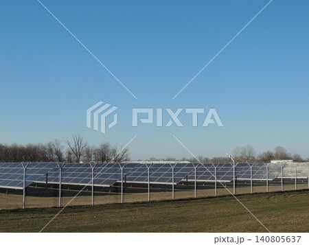 An industrial alternative energy production facility located in a vast open area. The station's territory is filled with long, perfectly aligned parallel rows of dark photovoltaic panels. An industrial alternative energy production facility located in a vast open area. The station's territory is filled with long, perfectly aligned parallel rows of dark photovoltaic panels. 140805637