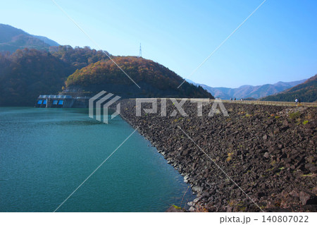 雄大な九頭竜ダムの風景。石積みが美しいロックフィルダムと秋の山々 雄大な九頭竜ダムの風景。石積みが美しいロックフィルダムと秋の山々 140807022