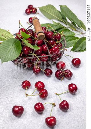 Fresh cherries filling metal basket with green leaves 140807145