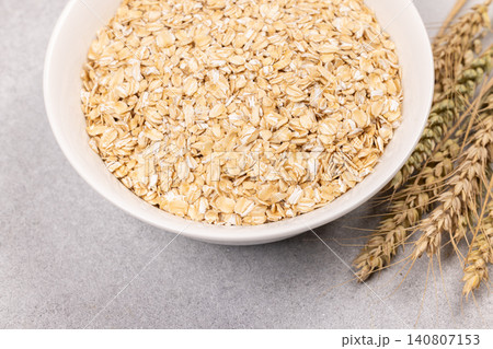 Raw oatmeal flakes in bowl with wheat ears Raw oatmeal flakes in bowl with wheat ears 140807153