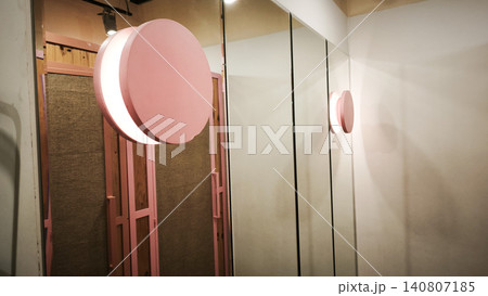 Public toilet interior exhibits stylish pink doors and large mirror wall panels. 140807185