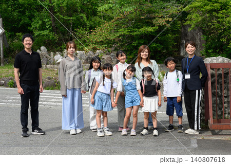 学校の校門の前で並ぶ先生と保護者と小学生の子供たちの集合写真 学校の校門の前で並ぶ先生と保護者と小学生の子供たちの集合写真 140807618