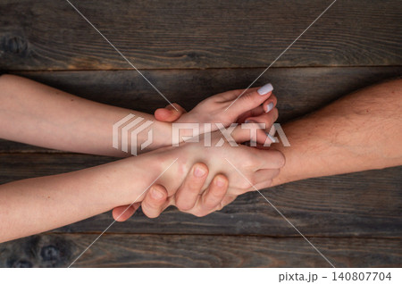 Strong man tightly grabs wrists of scared young woman against dark wooden table. Angry male abuser controls female victim by physical force. Domestic violence, aggression concept, toxic relationship Strong man tightly grabs wrists of scared young woman against dark wooden table. Angry male abuser controls female victim by physical force. Domestic violence, aggression concept, toxic relationship 140807704