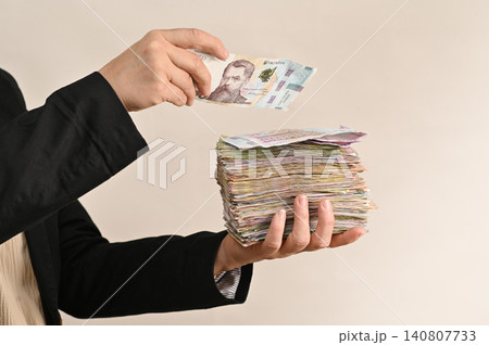 Individual embraces thick stacks of cash, symbolizing prosperity, 140807733