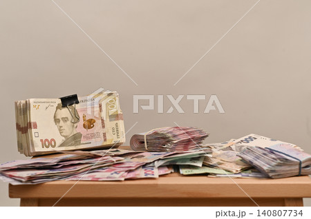 Ukrainian banknotes of different denominations stacked and spread on a table. Ukrainian banknotes of different denominations stacked and spread on a table. 140807734