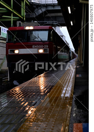 早朝の雨、駅を通過してゆく貨物列車 140807975