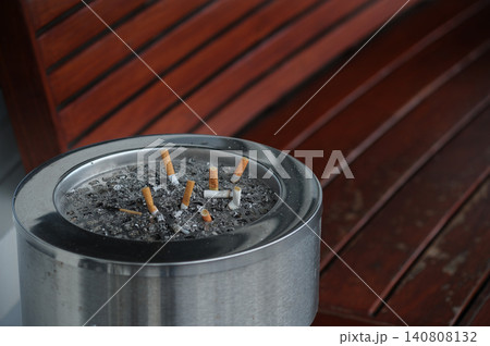 many cigarette stubs in the ashtyay near red bench at smoking area many cigarette stubs in the ashtyay near red bench at smoking area 140808132