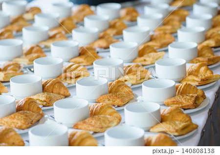 many line of croissant on a dish with empty coffee cups on the table ready to served for tea break in business conference many line of croissant on a dish with empty coffee cups on the table ready to served for tea break in business conference 140808138