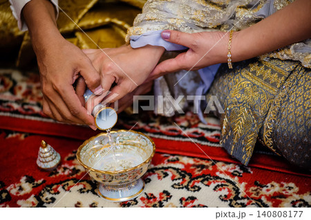 hands of the Bridge and groom holding together to pouring holy water to paying in Thai style traditional wedding ceremony. hands of the Bridge and groom holding together to pouring holy water to paying in Thai style traditional wedding ceremony. 140808177