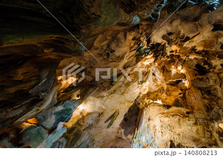 a cave with stalagmites and stalactites. The cave is large and dark, and the walls are covered in a variety of different rock formations. The stalagmites and stalactites are a variety of shapes and a cave with stalagmites and stalactites. The cave is large and dark, and the walls are covered in a variety of different rock formations. The stalagmites and stalactites are a variety of shapes and 140808213