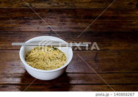 a white bowl of cooked instant noodles ready to eat with stainless steel chopsticks a white bowl of cooked instant noodles ready to eat with stainless steel chopsticks 140808267