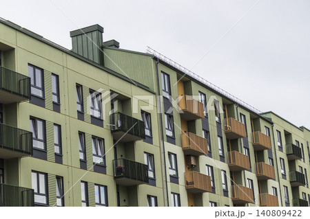 Low-angle diagonal view of a modern multi-colored apartment building row featuring green facades and bright yellow geometric balconies. Low-angle diagonal view of a modern multi-colored apartment building row featuring green facades and bright yellow geometric balconies. 140809422