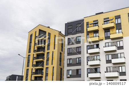 Modern residential building facade with geometric balconies, brick accent walls, and contemporary apartment block design. 140809517