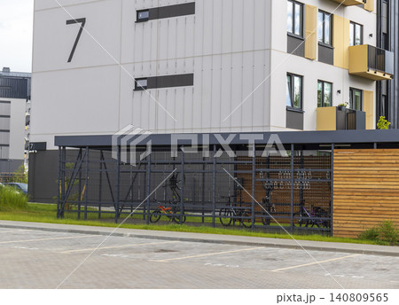 Modern secure bicycle storage locker and outdoor parking zone next to a contemporary residential apartment building. 140809565