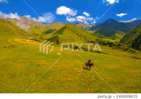 Cowboy on Horseback Riding in Kyrgyz Mountain Meadow Cowboy on Horseback Riding in Kyrgyz Mountain Meadow 140809635