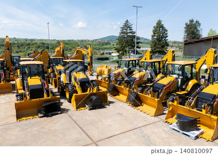 New hydraulic excavators and tractors parked at a construction machinery dealership New hydraulic excavators and tractors parked at a construction machinery dealership 140810097